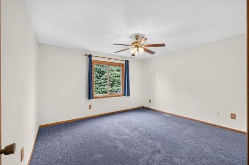 The primary bedroom offers a large window, neutral paint, and a ceiling fan.