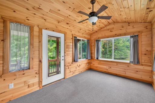 Wood walls and ceiling give the three-season porch a warm, cabin-inspired feel.