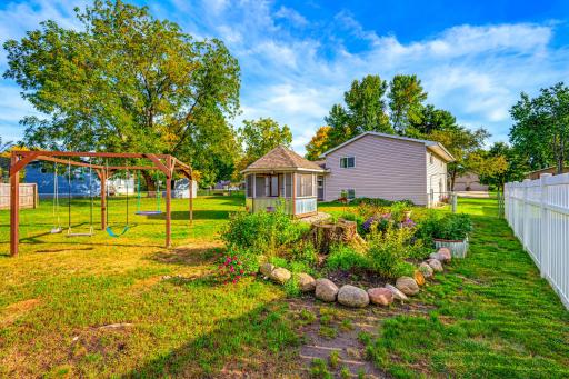 Beautiful flower gardens are featured in the backyard. The swing set will stay.