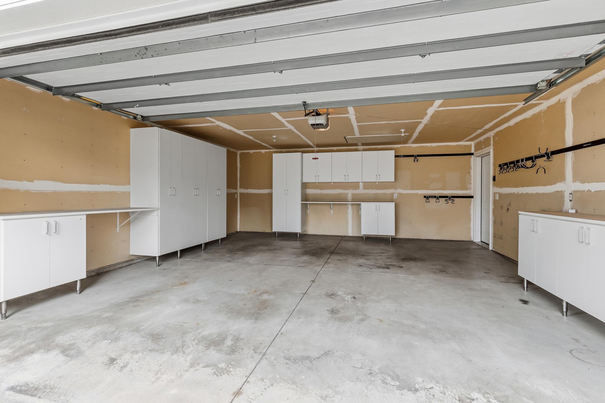 Two-car, deep garage has built in storage cupboards