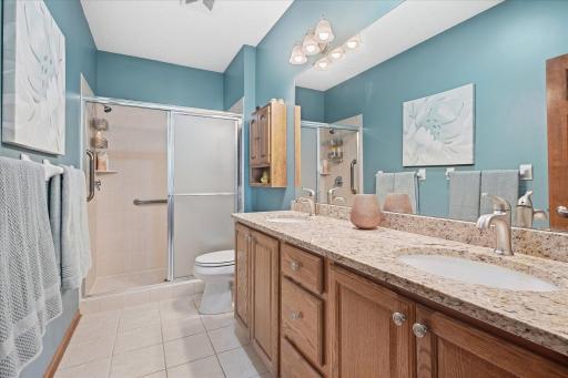 Thoughtfully renovated primary bath featuring granite countertops, a double vanity, tile flooring, and bright natural light from a solar tube!