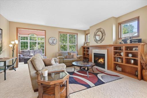 Bask in sun-filled main living space featuring a cozy gas fireplace framed by built-in shelving