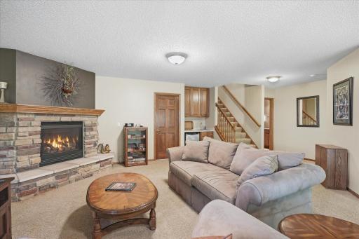 Spacious lower-level family room features a gorgeous stone fireplace and wet barâperfect for entertaining!