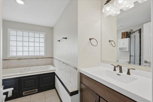 Main floor full bath with tile flooring and glass block window for privacy.