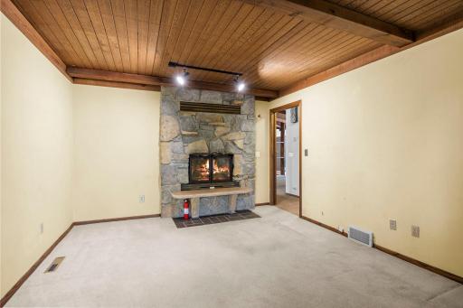 A striking double-sided stone fireplace creates a warm focal point while connecting the homeâs living spaces and office space with character and charm.