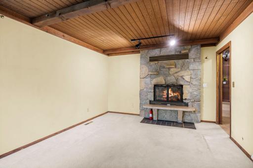 A striking double-sided stone fireplace creates a warm focal point while connecting the homeâs living spaces and office space with character and charm.