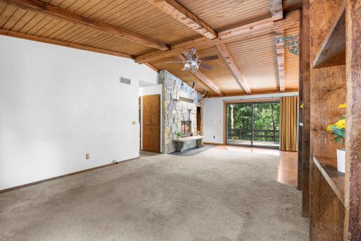Dramatic vaulted wood ceilings with exposed beams bring warmth and character to this spacious living area, highlighted by a striking floor-to-ceiling stone fireplace.