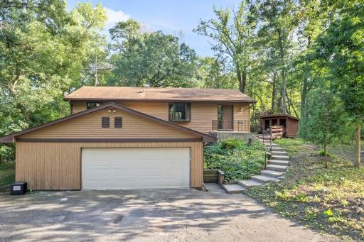 An attached garage, convenient front entry, and natural landscaping complement the home's warm, wooded surroundings.