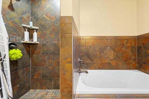The ensuite bathroom features a separate soaking tub and a tiled walk-in shower.