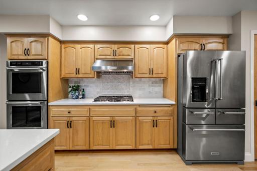 It pairs beautiful wood floors with a tile backsplash and stainless steel appliances, including double wall ovens.