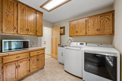 Finished laundry room with cabinetry, counterspace, and utility sink.