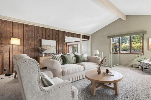 Comfortable and welcoming, the living room is ideal for quiet nights or entertaining family and friends. Vaulted ceilings and many windows create a bright open feel. Visually staged.