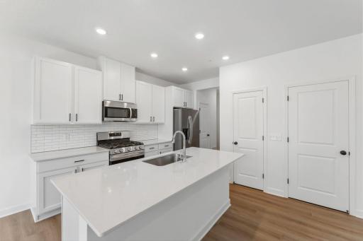 (All the following photos are of a similar home, actual finishes may vary.) This chef-ready kitchen is designed to accommodate modern living, with a center island to add seating space, gleaming quartz countertops and abundant cabinetry room.