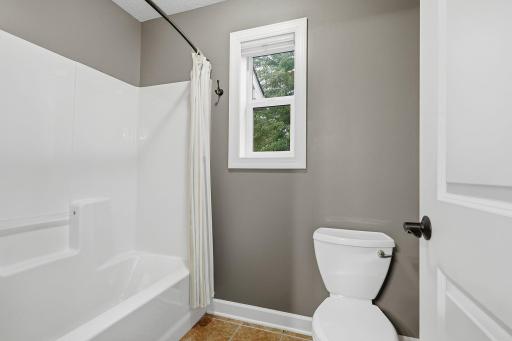 A separate space with door houses the tub/shower and toilet, providing added privacy and functionality. A window brings natural light into the space, while built-in shower shelving keeps bath essentials within easy reach.