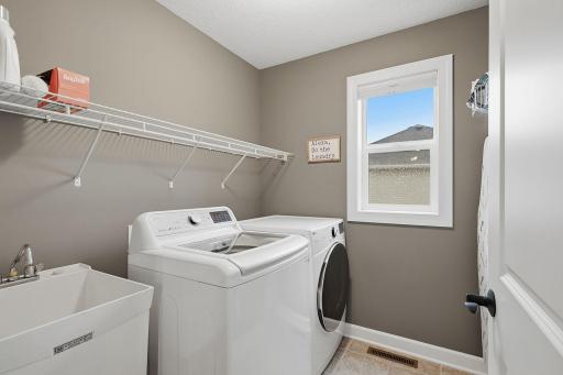 Conveniently located near the bedrooms, the dedicated laundry room features tile flooring, generous open shelving for supplies, a utility sink and a window for natural light.