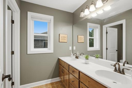 The upper-level full bath features a spacious double-sink vanity with abundant cabinetry, generous counter space and an oversized mirror.