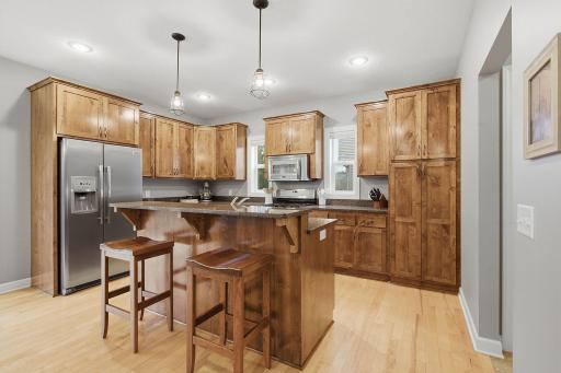 This spacious kitchen features warm knotty alder cabinetry & granite countertops, with a generous breakfast bar providing casual seating & a natural gathering spot. A custom pantry equipped with convenient slide-out drawers, maximizes accessibility