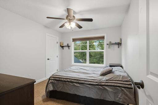 This upper-level bedroom features a large front-facing window with mature tree views, a spacious walk-in closet and ceiling fan. It is conveniently located near the full hall bath for easy access.