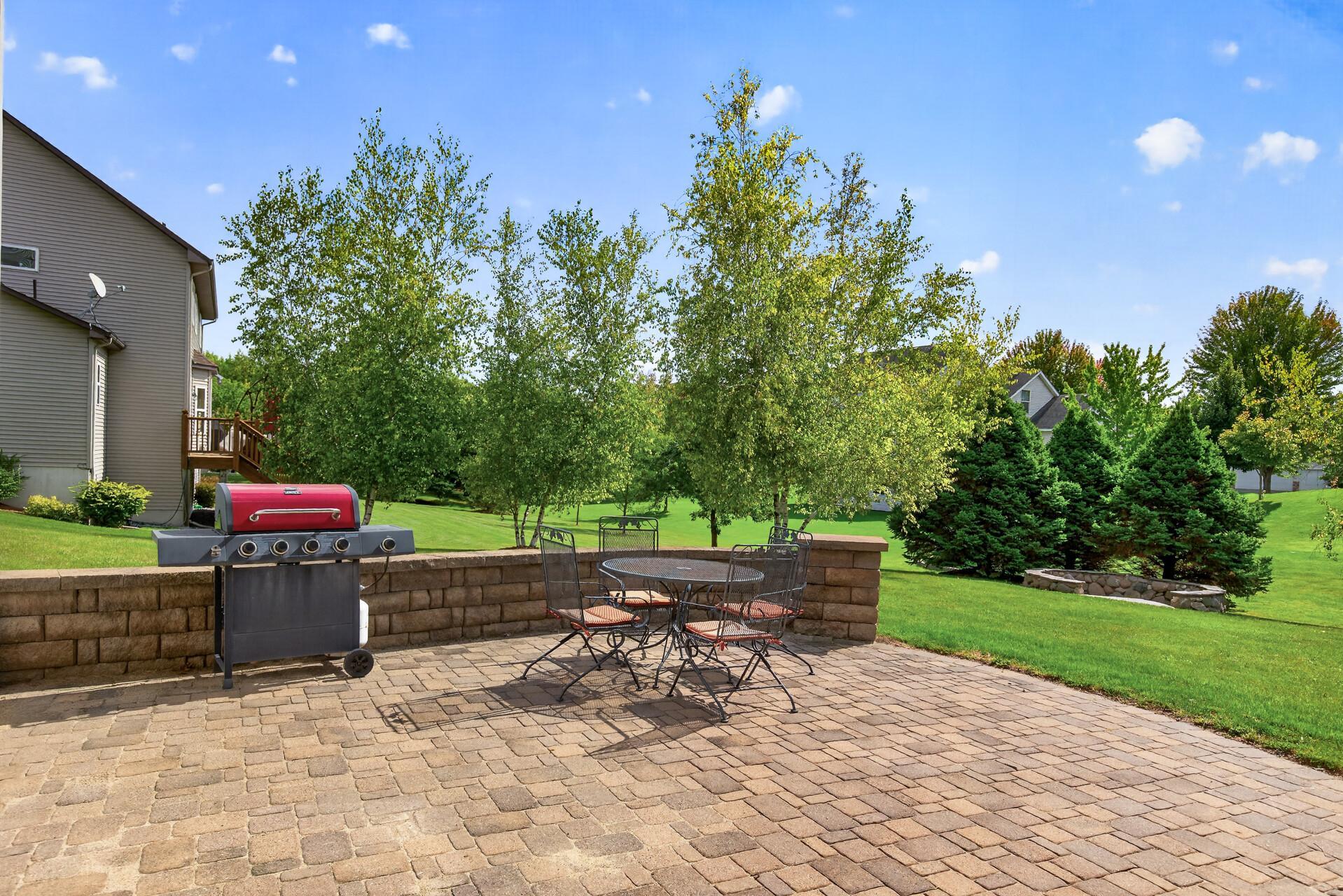Gracious paver patio with a stone wall adds to the charm.