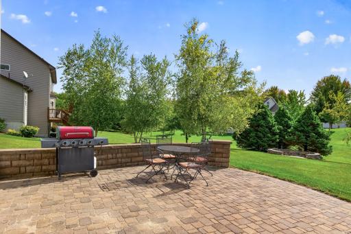 Gracious paver patio with a stone wall adds to the charm.