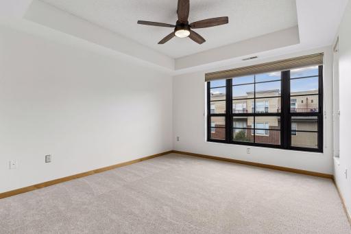 The primary bedroom features a tray ceiling and ceiling fan.