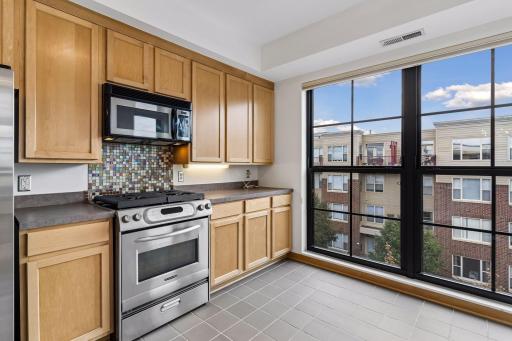 The kitchen features stainless steel appliances and a tile backsplash behind the gas range.