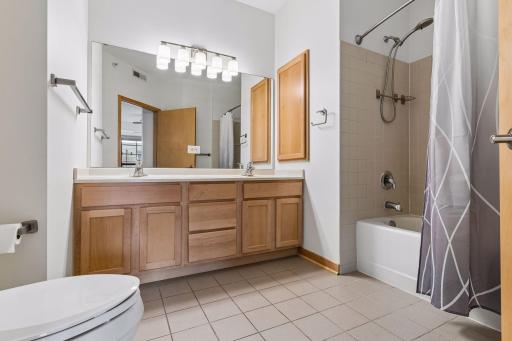The full bath features a long vanity with dual sinks, a deep linen cabinet, and a tub/shower combination.