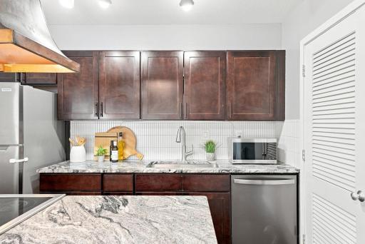 Updated kitchen featuring granite countertops, stainless steel appliances, and a custom backsplash.