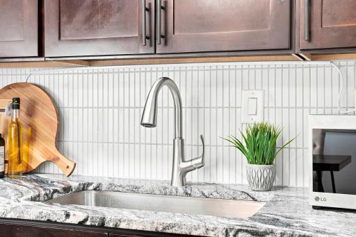 Updated sink and faucet pair beautifully with the custom backsplash and granite countertops.