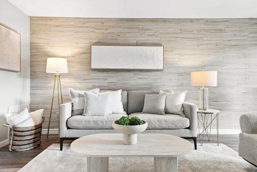 Bright, inviting, and thoughtfully updated, the main living space pairs warm flooring with a striking wood accent wall and an easy flow into the dining and kitchen areas.
