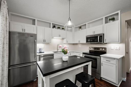 The center island adds valuable workspace and a natural gathering spot, while the crisp white cabinetry keeps the kitchen feeling fresh and open.