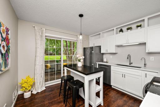 Bright, inviting kitchen featuring beautifully refaced white cabinetry, quartz countertops, stainless steel appliances and a spacious center island.