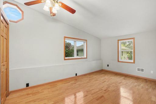 Main floor vaulted bedroom with a ceiling fan and extra octagon window to let in more light.