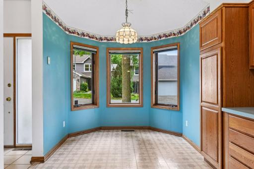 Kitchen opens to a bright dinette surrounded by windows overlooking the greenery.
