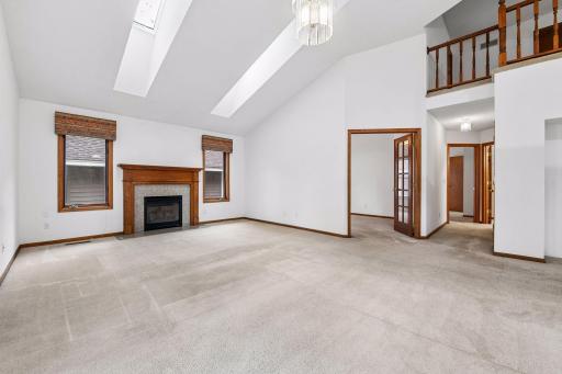 Spacious great room featuring soaring ceilings, skylights, and a cozy gas fireplace.