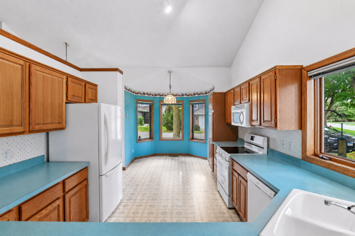 Functional kitchen with abundant cabinetry and an adjoining dinette surrounded by windows.