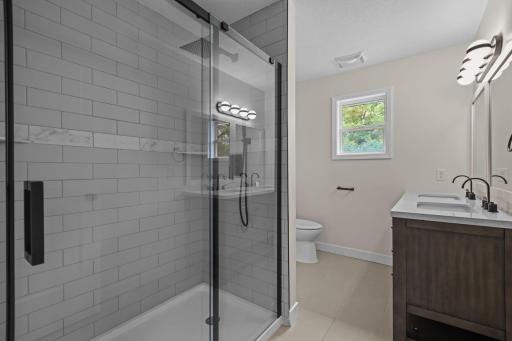 Remodeled main level bath complete with tiled shower surround, 10 inch rain head shower head, glass doors, new vanity and toilet, tiled floors.