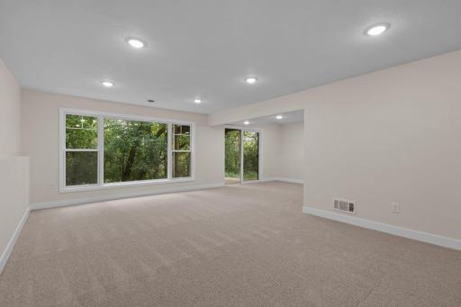 Lower family room with massive window and patio, allowing natural lighting and beautiful views of nature.