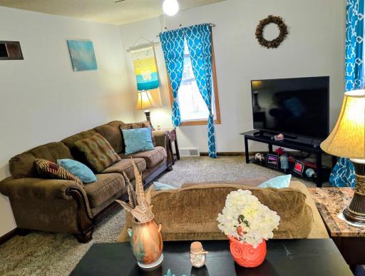 Carpeted living room area with ceiling fan