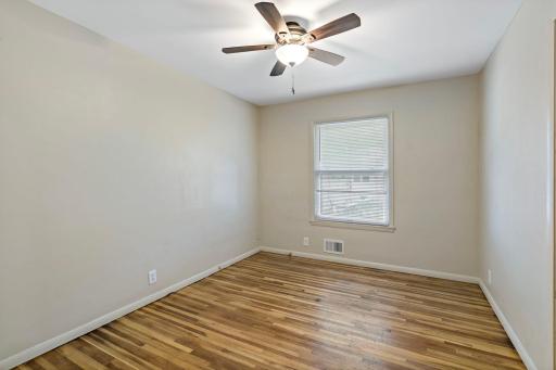 First bedroom with hardwood flooring and ceiling fan.