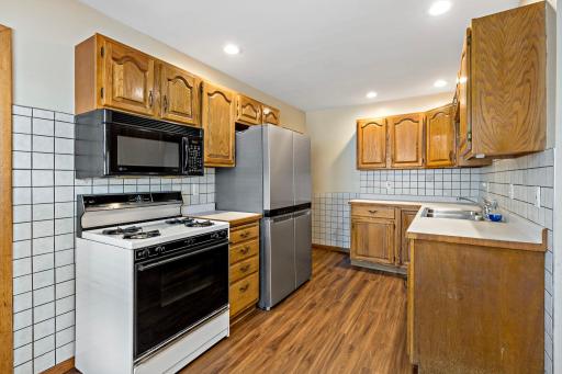 Kitchen with gas range, stainless steel refrigerator and laminate flooring.