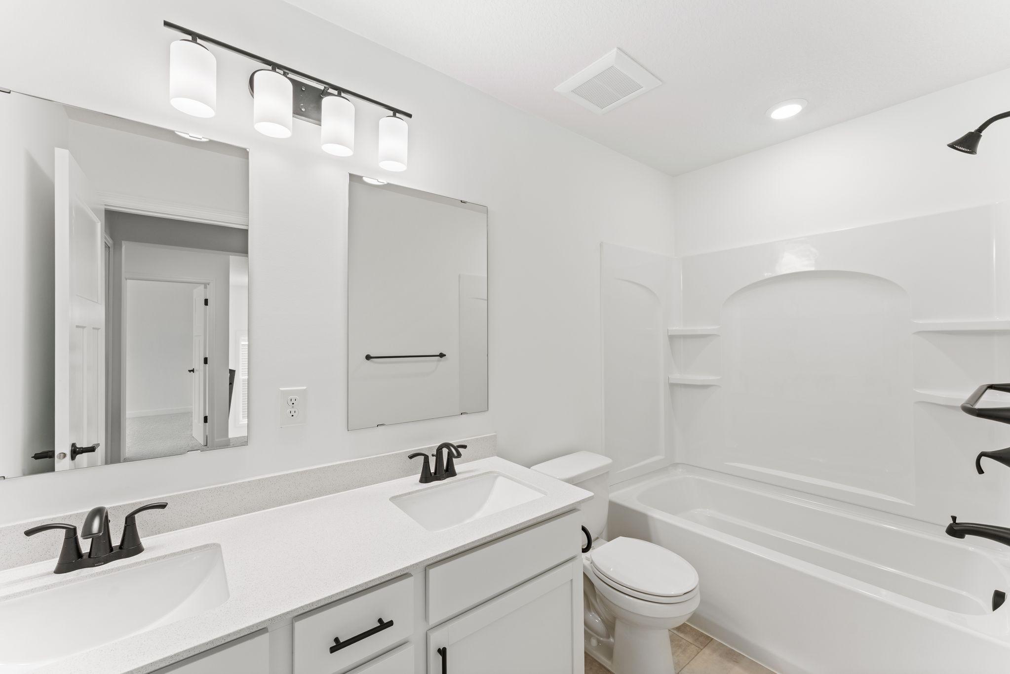 This shared full bathroom features dual sinks and a shower-tub combination.