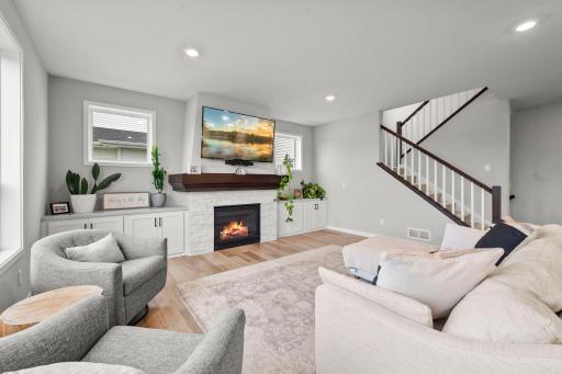 The living room becomes a natural gathering space, with a gas fireplace framed in white stone and built-ins.