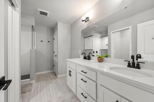 Dual vanities, additional storage, and walk-in tiled shower.