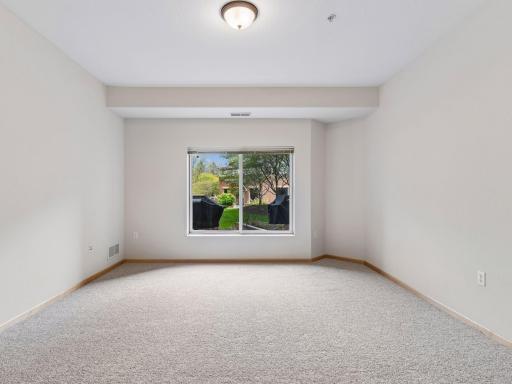 Light-filled primary bedroom with fresh carpeting and peaceful outdoor views.