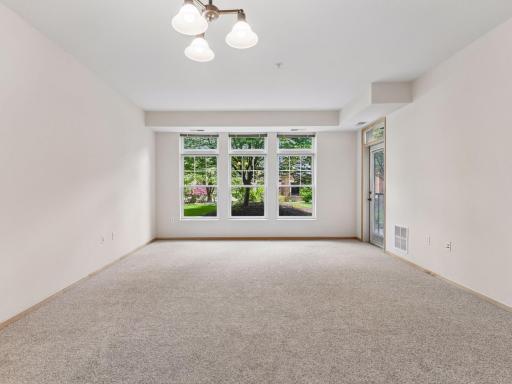 Expansive living room with fresh carpeting and beautiful courtyard views.