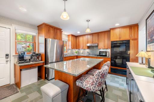 Warm oak cabinets (any plenty of them), large center island with seating, stainless appliances, tile backsplash, double wall oven, and fresh tile flooring.