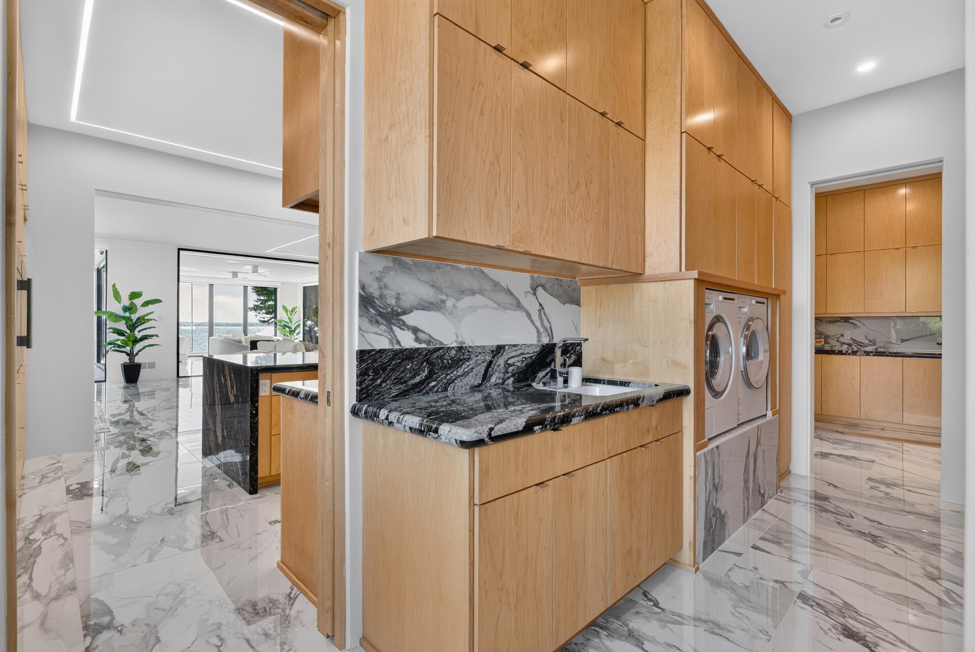 Multiple access points create an easy connection to the outdoors, including direct access to the mudroom with floor-to-ceiling organization, utility sink, and Asko washer and dryer.