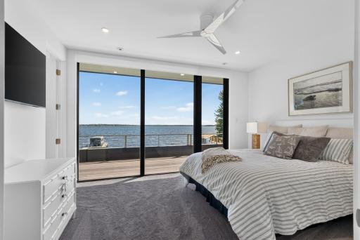 Three additional upper-level bedrooms are designed alike, each with modern ceiling fans, comfortable carpeting, and south-facing windows showcasing uninterrupted lake views. (Upper-level bedroom #2)