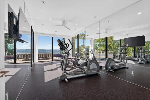 A dedicated fitness room features fitness flooring and floor-to-ceiling mirrors spanning several walls.